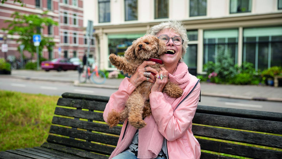 Dame op een bankje die een hond optilt