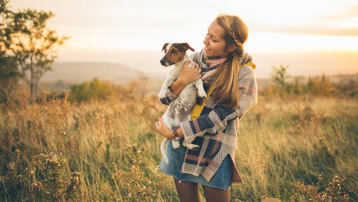 Vrouw met hond in armen op een grasveld